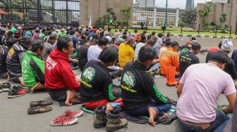 Pengemudi Ojol (Ojek Online) menggelar Salat Jumat bareng Polisi di depan Gedung  DPR dan MPR RI, Jakarta, Jumat (28/02). [Suara.com/Alfian Winanto]
