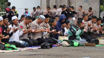 Para pengemudi Ojol (Ojek Online) berdoa usai Salat Jumat bareng Polisi di depan Gedung  DPR dan MPR RI, Jakarta, Jumat (28/02). [Suara.com/Alfian Winanto]
