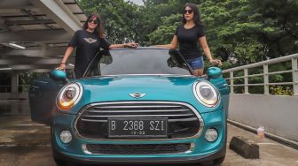 Anggota Indo MINI Club berpose di atas mobil Mini Cooper di kawasan Gelora Bung Karno, Senayan, Jakarta, Sabtu (29/02). [Suara.com/Alfian Winanto]
