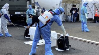 Petugas kesehatan menyemprotkan cairan disinfektan kepada WNI ABK Diamond Princess dan barang bawaan saat turun dari kapal di Yokohama, Jepang, Minggu (1/3). [ANTARA FOTO/HO/KBRI Tokyo]
