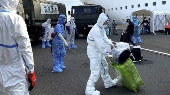 Petugas kesehatan bersiap menyemprotkan cairan disinfektan kepada WNI ABK Diamond Princess dan barang bawaan saat turun dari kapal di Yokohama, Jepang, Minggu (1/3). [ANTARA FOTO/HO/KBRI Tokyo]
