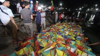 Sejumlah relawan haul KH Muhammad Zaini Abdul Ghani (Abah Guru Sekumpul) bergotong royong membersihkan beras di Irigasi Sekumpul, Martapura, Kalimantan Selatan, Sabtu (29/2) malam.[ANTARA FOTO/Bayu Pratama S] 