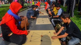 Warga mengikuti permainan tradisional "Lelempengan" pada peringatan Mieling Poe Basa Indung Sadunya atau Hari Bahasa Ibu Internasional di Alun-alun Kota Tasikmalaya, Jawa Barat, Minggu (1/3). [ANTARA FOTO/Adeng Bustomi]