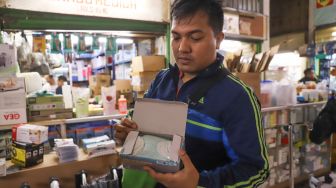 Pembeli menunjukan masker yang dibelinya di Pasar Pramuka,  Jakarta Timur, Senin (2/3). [Suara.com/Alfian Winanto]
