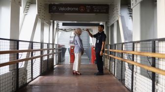 Petugas meriksa suhu tubuh seorang perempuan calon penumpang sebelum memasuki Stasiun LRT Velodrome, Rawamangun, Jakarta Timur, Selasa (3/3). [Suara.com/Angga Budhiyanto]