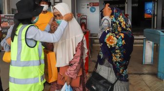 Petugas membantu memasangkan masker ke pengguna Commuterline di Stasiun Depok Baru, Depok, Jawa Barat, Selasa (3/3). [Suara.com/Alfian Winanto]