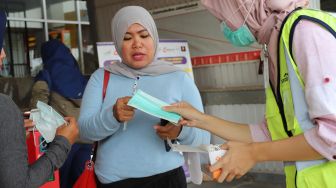 Petugas wanita membagikan masker ke pengguna Commuterline di Stasiun Depok Baru, Depok, Jawa Barat, Selasa (3/3). [Suara.com/Alfian Winanto]