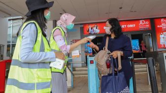 Petugas wanita membagikan masker ke pengguna Commuterline di Stasiun Depok Baru, Depok, Jawa Barat, Selasa (3/3). [Suara.com/Alfian Winanto]