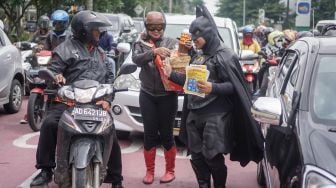 Tokoh superhero batman dan gundala melakukan aksi sosialisasi pencegahan virus corona dan mambagikan jamu kepada pengguna jalan di Solo Baru, Sukoharjo, Jawa Tengah, Rabu (4/3).  [ANTARA FOTO/Mohammad Ayudha]
