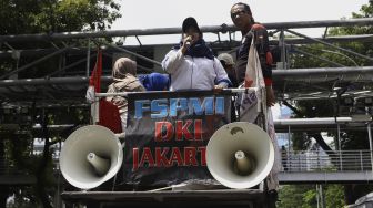 Sejumlah massa buruh perempuan yang tergabung dalam Federasi Serikat Pekerja Metal Indonesia (FSPMI) - Konfederasi Serikat Pekerja Indonesia (KSPI) berorasi diatas mobil menuju depan gedung Kementerian Pemberdayaan Perempuan dan Perlindungan Anak Republik Indonesia, Jalan Medan Merdeka Barat, Jakarta Pusat, Jumat (6/3). [Suara.com/Angga Budhiyanto]