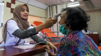 Seorang wanita diperiksa suhu tubuhnya dalam sosialisasi pencegahan virus corona yang digelar PT KAI Daop 1 melalui Rail Clinic di Stasiun Depok, Jawa Barat, Jumat, (6/3). [Suara.com/Alfian Winanto]