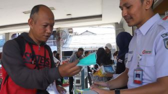 Petugas membagikan masker kepada penumpang di Stasiun Depok, Jawa Barat, Jumat (6/3). [Suara.com/Alfian Winanto]