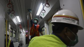 Petugas membersihkan bagian atap pada rangkaian kereta Light Rapid Transit (LRT) di Depo LRT Jakarta, Kelapa Gading, Jakarta Timur, Jumat (6/3).  [Suara.com/Angga Budhiyanto]

