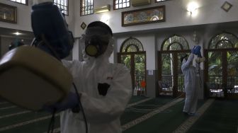 Petugas menyemprotkan cairan disinfektan di Masjid Nurul Hidayah, Jalan Brawijaya XII, Jakarta Selatan, Minggu (8/3). [Suara.com/Angga Budhiyanto]