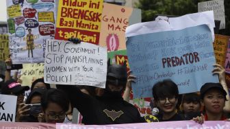 Massa yang tergabung dalam Aliansi Gerakan Perempuan Anti-Kekerasan (GERAK Perempuan) menggunakan kostum Batman saat melakukan aksi unjuk rasa di depan kantor Bawaslu, Jakarta, Minggu (8/3). [Suara.com/Angga Budhiyanto]