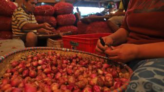 Pedagang mengupas bawang merah di Pasar Induk Kramat Jati, Jakarta Timur, Selasa (10/3). [Suara.com/Alfian Winanto]
