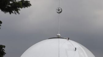 Aksi pekerja dengan pengaman lengkap melakukan pengecatan pada bagian kubah Masjid Istiqlal, Jakarta, Selasa (10/3).  [Suara.com/Angga Budhiyanto]
