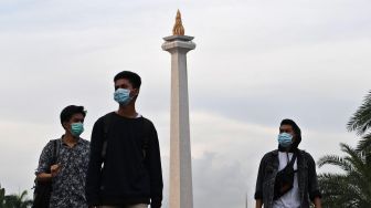 Sejumlah warga dengan menggunakan masker berjalan di kawasan Monumen Nasional, Jakarta, Rabu (11/3). [ANTARA FOTO/Aditya Pradana Putra]