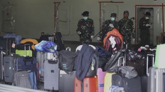 Anggota TNI menyemprotkan cairan desinfektan ke barang-barang milik WNI Anak Buah Kapal (ABK) World Dream tiba di Dermaga Komando Lintas Laut Militer (Kolinlamil), Tanjung Priok, Jakarta Utara, Sabtu (14/3). [Suara.com/Angga Budhiyanto]