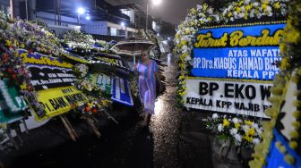 Warga melintasi karangan bunga yang terpasang di rumah duka almarhum Kepala Pusat Pelaporan Analisis dan Transaksi Keuangan (PPATK) Kiagus Ahmad Badaruddin di Tebet, Jakarta, Sabtu (14/3).   [ANTARA FOTO/Aditya Pradana Putra]