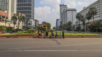 Pesepeda berpose di kawasan Bundaran Hotel Indonesia (HI) di Jalan Sudirman - Thamrin, Jakarta, Minggu (15/3). [Suara.com/Alfian Winanto]