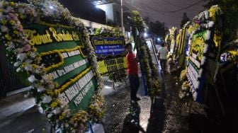 Warga memindahkan karangan bunga yang terpasang di rumah duka almarhum Kepala Pusat Pelaporan Analisis dan Transaksi Keuangan (PPATK) Kiagus Ahmad Badaruddin di Tebet, Jakarta, Sabtu (14/3).   [ANTARA FOTO/Aditya Pradana Putra]