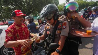 Warga membagikan jamu tradisional secara gratis ke Polisi di Jalan RTA Milono, Palangkaraya, Kalimantan Tengah, Senin (16/3).   [ANTARAFOTO/Makna Zaezar]