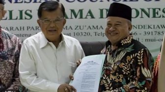 Wakil Ketua Umum MUI Muhyiddin Junaidi (kanan) menyerahkan naskah Fatwa Nomor 14 Tahun 2020 tentang penyelenggaraan ibadah dalam situasi wabah COVID-19 kepada Ketua Umum Dewan Masjid Indonesia (DMI) Jusuf Kalla di Jakarta, Selasa (17/3/2020). [Suara.com /Alfian winanto]