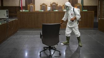 Petugas PMI Kota Jakarta Pusat menyemprotkan cairan disinfektan di kursi ruangan sidang Pengadilan Tipikor, Jakarta, Rabu (18/3).   [ANTARA FOTO/Galih Pradipta]