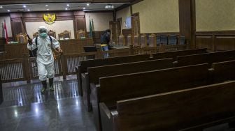 Petugas PMI Kota Jakarta Pusat menyemprotkan cairan disinfektan di bangku ruangan sidang Pengadilan Tipikor, Jakarta, Rabu (18/3).   [ANTARA FOTO/Galih Pradipta]