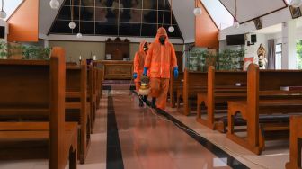 Petugas menyemprotkan disinfektan di bagian dalam Gereja Katolik Santa Catharina di kawasan Taman Mini Indonesia Indah (TMII), Jakarta Timur, Rabu (18/3). [Suara.com/Alfian Winanto]
