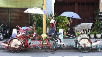 Seorang pengemudi becak mencari penumpang di Penang Malaysia, Rabu (18/3). [GOH CHAI HIN / AFP]
