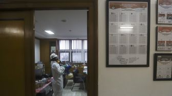 Petugas melakukan penyemprotan cairan disinfektan pada ruang kerja gedung Komisi Pemilihan Umum (KPU) Republik Indonesia, Jakarta, Jumat (20/3). [Suara.com/Angga Budhiyanto]