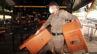 Petugas Satpol PP Kota Pontianak mengangkat sejumlah kursi untuk disimpan ke dalam warung kopi saat melakukan penertiban di Pontianak, Kalimantan Barat, Jumat (20/3).  [ANTARA FOTO/Jessica Helena Wuysang]