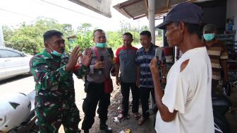 Bripka Indra Bayu (kedua kiri) dan Sertu Miseli (kiri) keliling kampung memberikan imbauan pencegahan COVID-19 di Tegal Sari, Banyuwangi, Jawa Timur, Sabtu (21/3). [ANTARA FOTO/Budi Candra Setya]