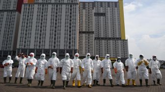 Petugas Palang Merah Indonesia (PMI) berjalan untuk melakukan penyemprotan cairan disinfektan pada Wisma Atlet di Kemayoran, Jakarta, Sabtu (21/3). [ANTARA FOTO/M Risyal Hidayat]
