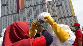 Petugas Palang Merah Indonesia (PMI) memakai kacamata pelindung untuk melakukan penyemprotan cairan disinfektan pada Wisma Atlet di Kemayoran, Jakarta, Sabtu (21/3). [ANTARA FOTO/M Risyal Hidayat]