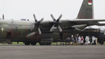 Petugas memindahkan muatan alat kesehatan dari Pesawat Hercules C-130 saat mendarat di Landasan Udara (Lanud) Halim Perdanakusuma, Jakarta, Senin (23/3).[Suara.com/Angga Budhiyanto]