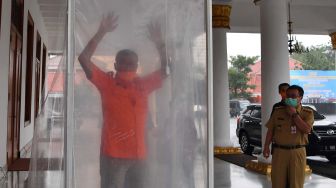 Warga memasuki bilik disinfektan atau bilik sikat Corona (Sico) ketika keluar dari Gedung Negara Grahadi di Surabaya, Jawa Timur, Senin (23/3). (COVID-19). ANTARA FOTO/Zabur Karuru
