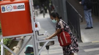 Seorang wanita cuci tangan di fasilitas tempat mencuci tangan untuk umum di kawasan Senayan, Jakarta, Senin (23/3). [Suara.com/Angga Budhiyanto]