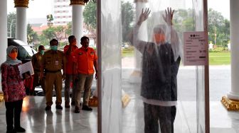 Gubernur Jawa Tirmur Khofifah Indar Parawansa (kanan) memasuki bilik disinfektan atau bilik sikat Corona (Sico) ketika memasuki Gedung Negara Grahadi di Surabaya, Jawa Timur, Senin (23/3).  [ANTARA FOTO/Zabur Karuru]
