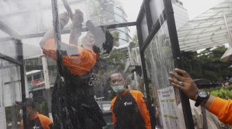 Petugas melakukan pemasangan Disinfection Chamber di kawasan Blok M, Jakarta Selatan, Selasa (24/3). [Suara.com/Angga Budhiyanto]