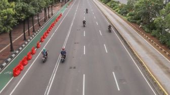 Kendaraan bermotor melintas di Jalan M.H Thamrin, Jakarta, Selasa (24/3). [Suara.com/Alfian Winanto]