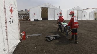 Petugas Palang Merah Indonesia (PMI) menggotong alat darurat di Gudang Logistik Darurat Penanganan virus Corona COVID-19 di Jalan Gatot Soebroto, Jakarta, Rabu (25/3).  [Suara.com/Angga Budhiyanto]