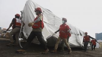 Petugas Palang Merah Indonesia (PMI) menggotong tenda darurat di Gudang Logistik Darurat Penanganan virus Corona COVID-19 di Jalan Gatot Soebroto, Jakarta, Rabu (25/3).  [Suara.com/Angga Budhiyanto]