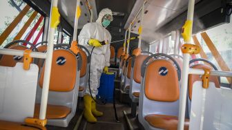 Petugas menyemprotkan cairan disinfektan di bus Transjakarta usai menjemput petugas medis dari RSUD Pasar Minggu di Hotel Grand Cempaka Bisnis, Jakarta, Sabtu (28/3). [ANTARA FOTO/Galih Pradipta]