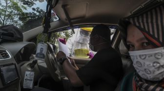 Petugas Dinas Kesehatan Kota Depok melakukan pengecekan kepada pengguna kendaraan saat tes cepat (rapid test) COVID-19 dengan sistem "drive thru" di Cimanggis, Depok, Jawa Barat, Minggu (29/3). [ANTARA FOTO/Muhammad Adimaja]