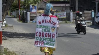 Seorang pria berkeliling sambil mengenakan topeng dan membawa sejumlah imbauan guna mengajak masyarakat membantu penanganan virus Corona (COVID-19) di Palu, Sulawesi Tengah, Minggu (29/3). [ANTARA FOTO/Mohamad Hamzah]