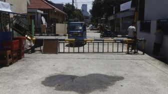 Suasana di depan portal saat diberlakukannya penutupan akses wilayah di Komplek Pondok Jaya, Mampang Prapatan, Jakarta Selatan, Selasa (31/1). [Suara.com/Angga Budhiyanto]