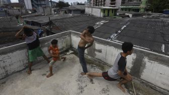 Sejumlah warga berjemur sambil melakukan olahraga kecil di balkon rumahnya di permukiman padat di kawasan Pejompongan, Jakarta, Selasa (7/4). [Suara.com/Angga Budhiyanto]